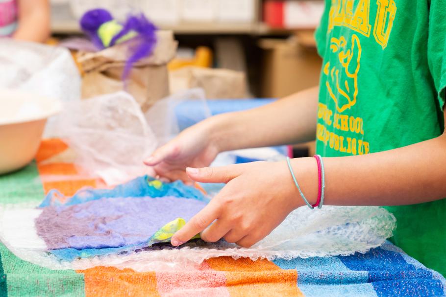 Two hands place coloured paper over bubble wrap. 