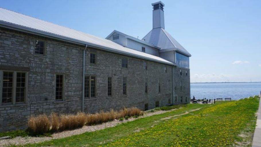 Side view of the Tett Centre, showing limestone walls, the Malting Tower, and the lake. 