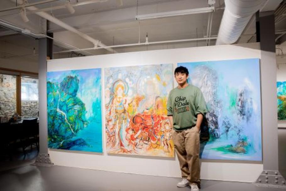 Image of Peng in front of three brightly coloured paintings