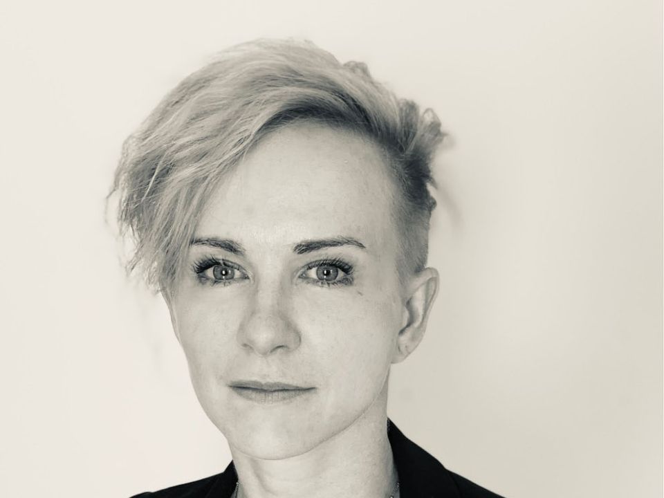 Headshot of Emily Skoggard, with light-coloured short hair and wearing a blazer. 