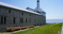 Side view of the Tett Centre, showing limestone walls, the Malting Tower, and the lake. 