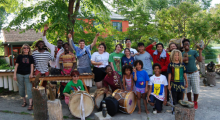 A large group of BIPOC teens outside with drums. 